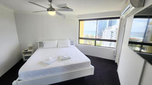 1 dormitorio con 1 cama blanca y 2 toallas en Surfers Hawaiian Holiday Apartments, en Gold Coast