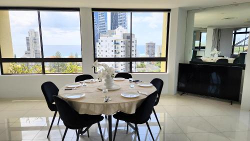 comedor con mesa, sillas y ventanas en Surfers Hawaiian Holiday Apartments, en Gold Coast
