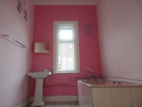 baño con lavabo, bañera y ventana en Swartkops Cann-a-bee Air B&B en Gqeberha