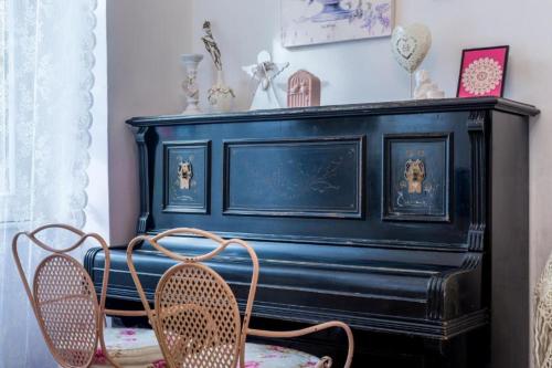 un piano negro en una habitación con 2 sillas en House Ingrid, en Rijeka