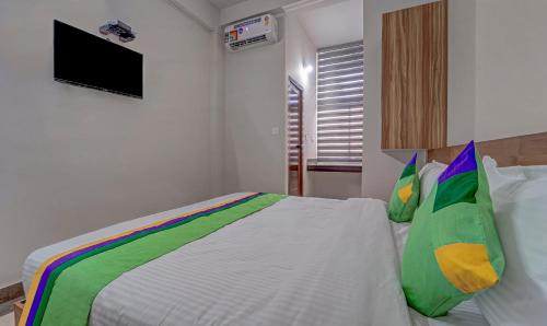 a bedroom with a white bed with colorful pillows at Treebo Regalia Inn Wayanad in Kalpetta