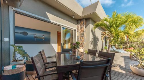 a patio with a glass table and chairs on a deck at Villa Sartelo in Tamarin