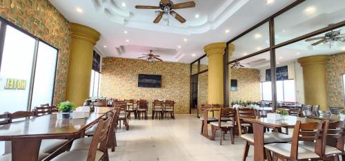 a restaurant with wooden tables and chairs and windows at Royal Sweet Hotel in Patong Beach