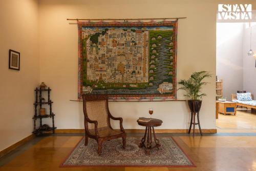 a rug hanging on a wall next to a chair and a chair at StayVista's Wildwood Canopy - Forest-View, Pet-Friendly Villa with Lawn & Indoor-Outdoor Games in Jaipur