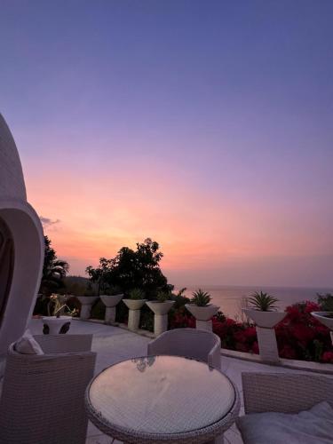 a patio with chairs and tables and a sunset at Villa Dreamdome in Teluk Nara