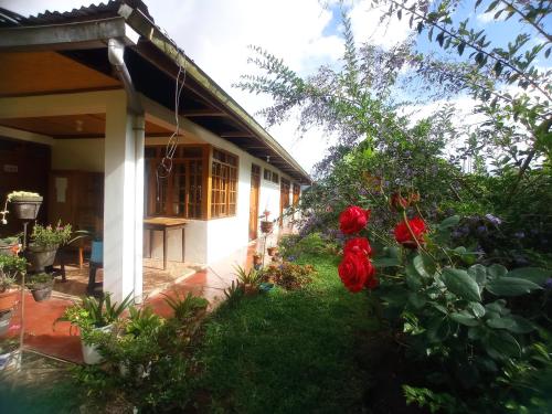 une maison avec des fleurs rouges dans la cour dans l'établissement Hospedaje Pinky Lodge, à Oxapampa