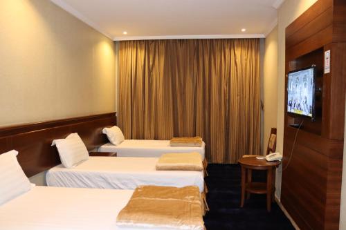 um quarto de hotel com três camas e uma televisão de ecrã plano em فندق ضيوف المقام للغرف والشقق المفروشة em Meca