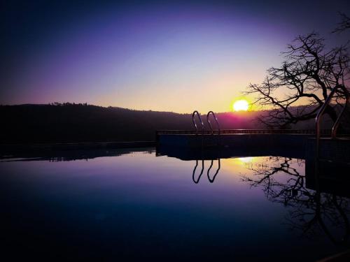 een zonsondergang boven een waterlichaam met zonsondergang bij Vibez Panchgani by Zen Nest in Panchgani