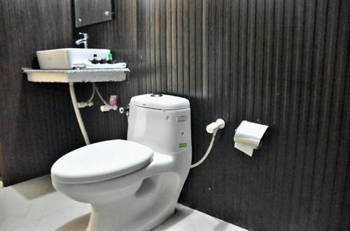 a bathroom with a white toilet and a sink at UPASANA THE RIVER SIDE RESORT in Marchula