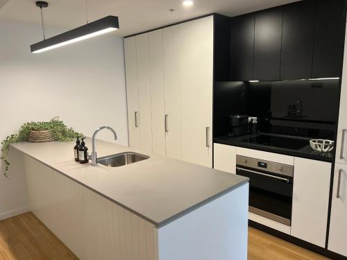a kitchen with black and white cabinets and a sink at NEW BOUTIQUE 1bd Apt in Canberra
