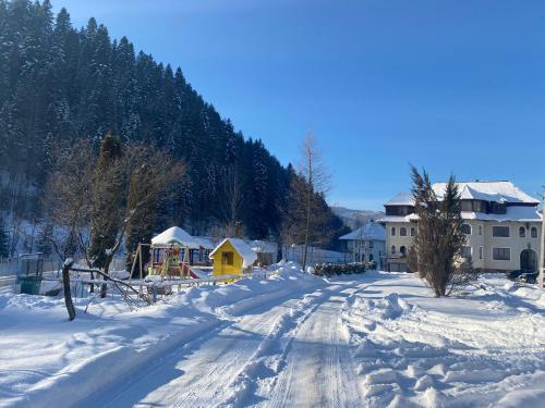 a snow covered street with a house and a playground at Садиба "Джерело" in Yaremche