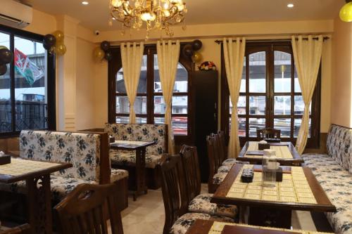 a restaurant with tables and chairs and a chandelier at Hotel BENTLY Terminal-2 in Mumbai
