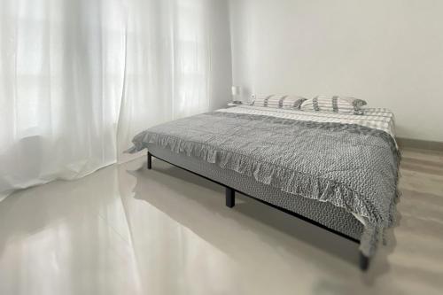a bed in a white room with a white curtain at Verse Guest House in Pontianak