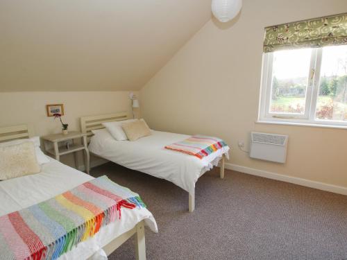 1 dormitorio con 2 camas y ventana en Brynlikky Cottage, en Bucknell