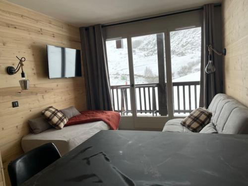 une chambre avec un canapé, une table et une fenêtre dans l'établissement f2 28 m2 n°405 5 personnes ski au pied/piscine, à Valmeinier
