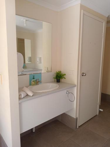 een witte badkamer met een wastafel en een spiegel bij Hervey Bay Flashpackers in Hervey Bay