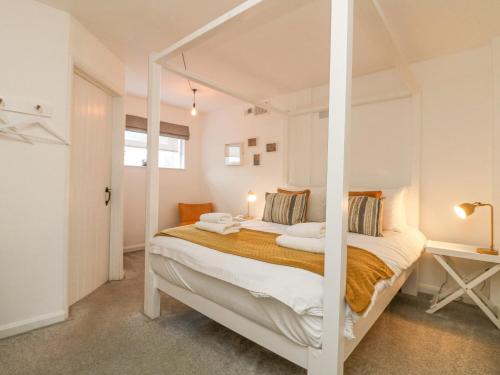 a white bedroom with a bed with a canopy at The Old Post Office in Helston