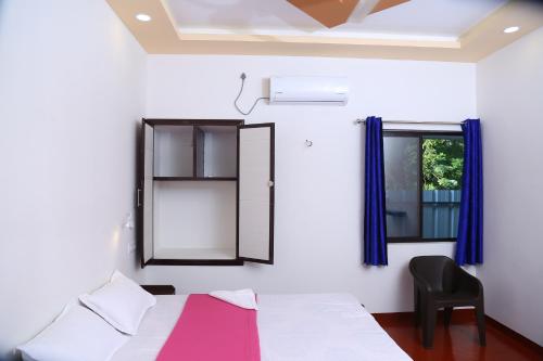 une chambre avec un lit, une chaise et une fenêtre dans l'établissement Marari Lois Beach Homes, à Mararikulam