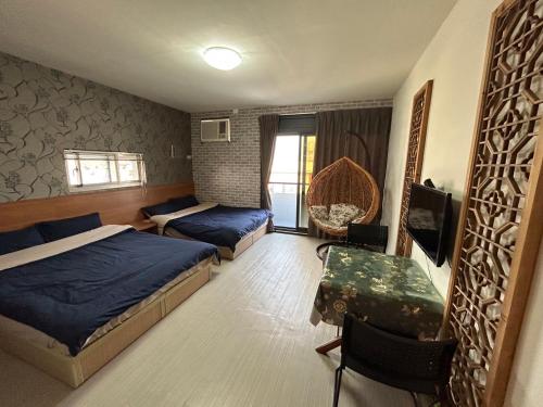 1 dormitorio con 2 camas y mesa. en 若華軒民宿Ruohuaxuan, en Fang-liao