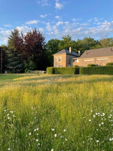 a field of grass with a house in the background at Domaine De L'Ardoisiere in Alle