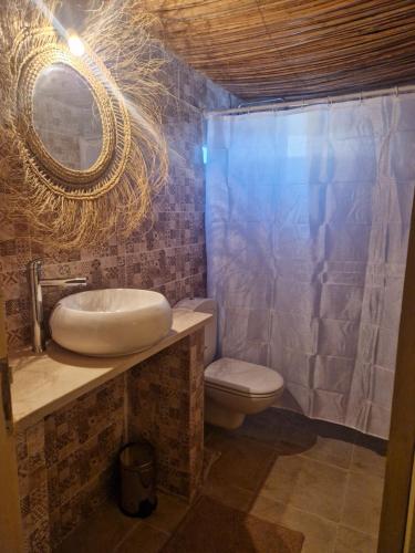 uma casa de banho com um lavatório, um WC e um espelho. em Les Bungalows d'Armelle em Tozeur
