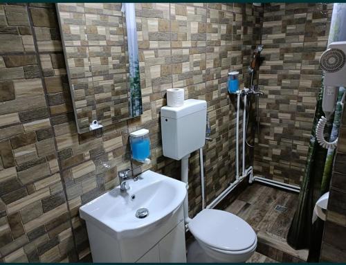 ein Badezimmer mit einem weißen WC und einem Waschbecken in der Unterkunft Casa Bianca Pensiune in Târgu Jiu