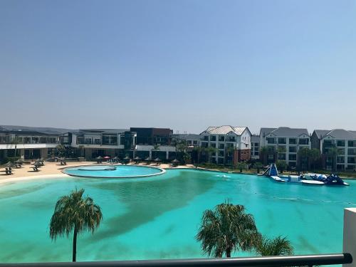 a large swimming pool with palm trees and buildings at Contemporary unit at the Blyde in Pretoria