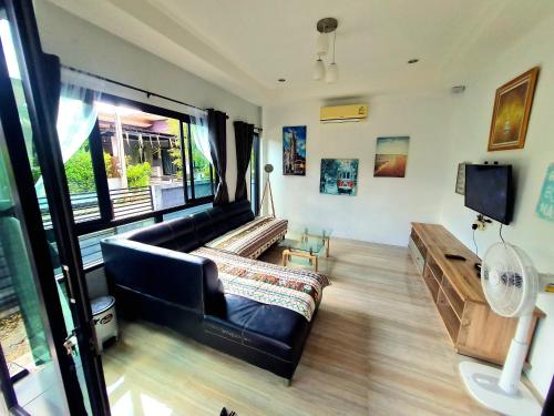 a living room with a black leather couch and a tv at Comfy house near sunset beach in Koh Samui