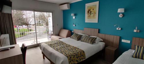 a bedroom with a bed with a blue wall at Logis Hôtel Les Bleuets in Royan