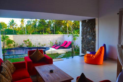 a living room with red furniture and a pool at Ratna Villa in Ubud