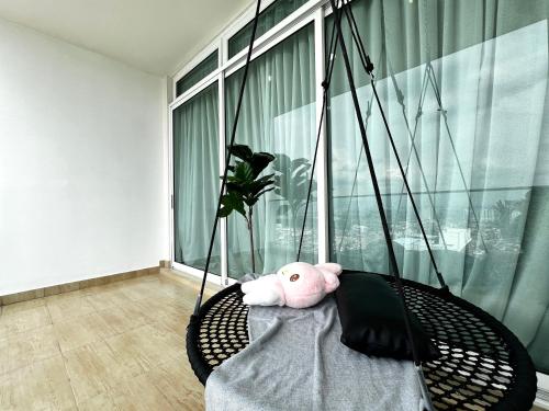 a pink teddy bear sitting on a swing in a room at KSL Desplanade By Antlerzone in Johor Bahru