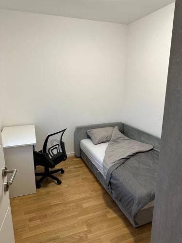 Un pequeño dormitorio con una cama y una silla. en Plava Zvezda 1, en Novi Sad