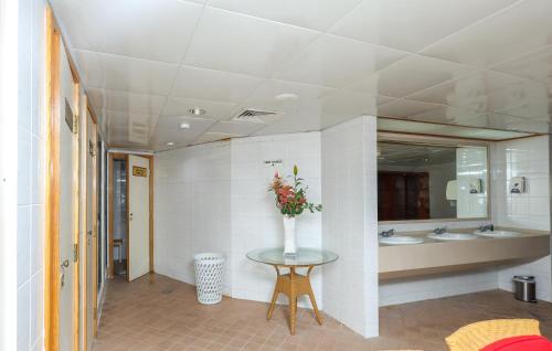La salle de bains est pourvue de 2 lavabos et d'un vase de fleurs sur une table. dans l'établissement Aavri Hotel, à Dubaï
