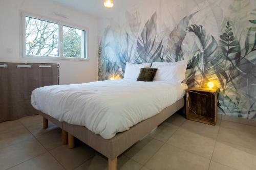 - une chambre avec un grand lit et du papier peint tropical dans l'établissement Appart Hôtel La Gacilly-centre ville-SPA-parking, à La Gacilly