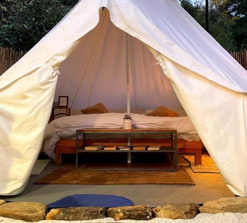 a tent with a bed and a table in it at Bell Glamping - Luxury Bath in Mukteshwar's Nature in Mukteswar