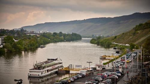 a river with a bunch of cars and a ferry at Moselhotel Römischer Kaiser in Bernkastel-Kues