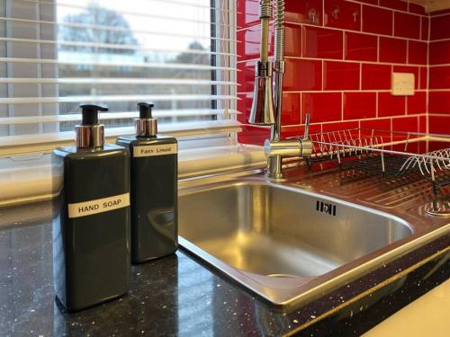 two bottles sitting on a kitchen counter next to a sink at BrumStay UK® 5-Bed House Ideal for Long-Term Stays in Birmingham