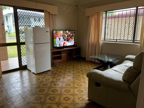 a living room with a white refrigerator and a couch at Aspley large room & share bathroom with other guests in Brisbane