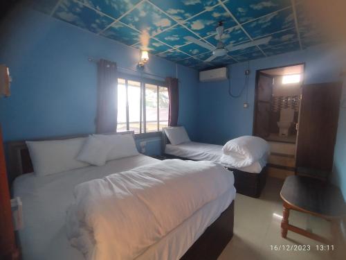 um quarto com 2 camas e uma parede azul em Rose Guest House em Jogīkuti