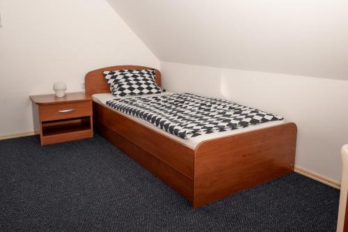 - un petit lit dans une chambre avec une table de nuit dans l'établissement Apartmajske hiške Lubadarček, à Podčetrtek