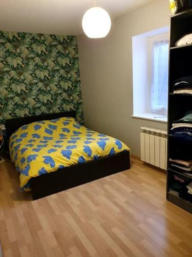 CraponneにあるAppartement, Terrasse et jardinのベッドルーム1室(黄色と青の毛布付きのベッド1台付)