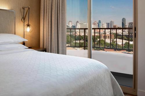 a hotel room with a bed and a large window at Sheraton Suites Market Center Dallas in Dallas