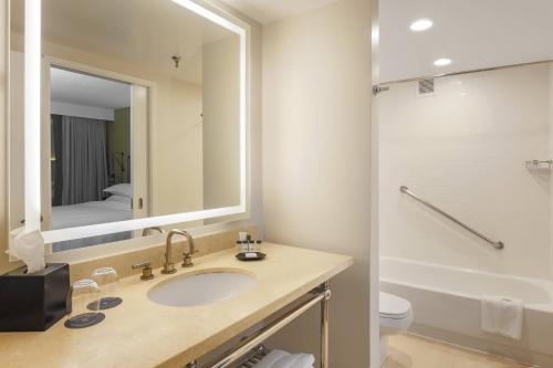 a bathroom with a sink and a toilet and a mirror at Sheraton Suites Market Center Dallas in Dallas