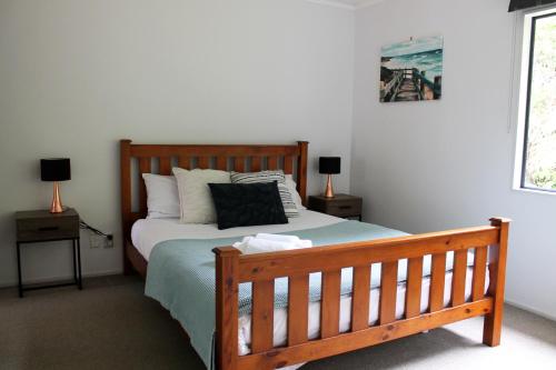 una camera con letto in legno e 2 comodini di Orchid Lane Bay of Island a Haruru