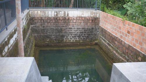 uma piscina de água junto a uma parede de tijolos em Kaanayi heritage home em Kokkānisseri