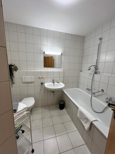 a white bathroom with a tub and a sink at DG-Wohnung in Waldkraiburg 50qm in Waldkraiburg