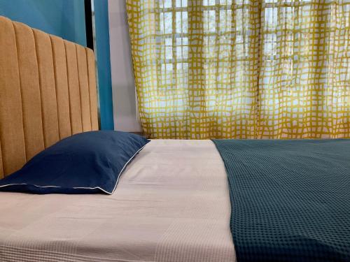 a bed with a blue pillow in front of a window at Zorba the Buddha in Begusarai