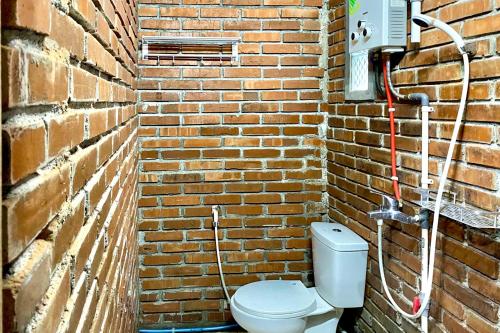 eine Backsteinwand mit einem WC in einem Backsteinbad in der Unterkunft TwoSpaces Living at Pondok Pakde, Jogja in Soprayan