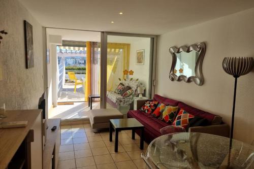 un salon avec un canapé rouge et une table en verre dans l'établissement Naturiste Cap d'Agde Port Ambonne 103, au Cap d'Agde