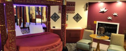 a bedroom with a canopy bed and a table and chairs at Inn of the Dove - Romantic Luxury Suites with Jacuzzi & Seasonal Fireplace at Harrisburg-Hershey-Philadelphia, PA in Harrisburg